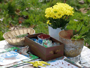 Paints, paper and flowers on a makeshift table